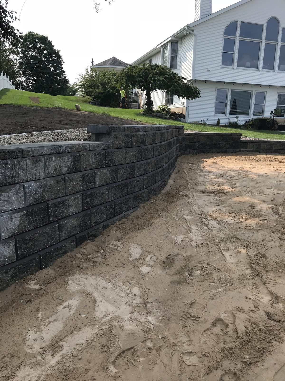 Curved gray block retaining wall under construction at a West Michigan home